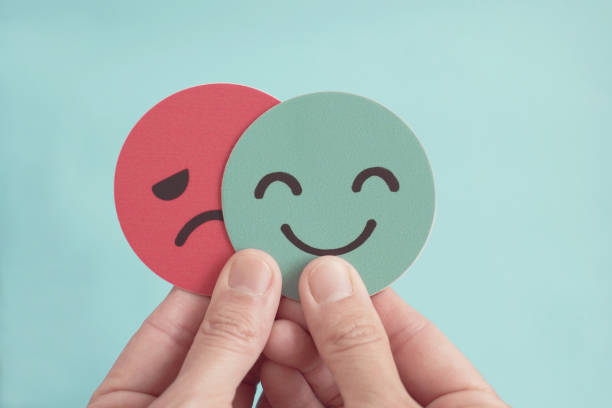 istock Hands holding sad face hiding behind happy face, bipolar and depression, mental health, split personality,  mood change concept 1365749449