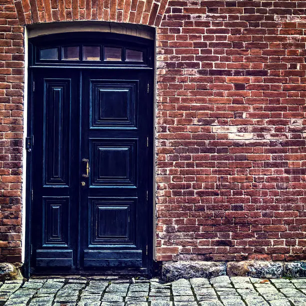 Closed Black Door and Old Brick Wall