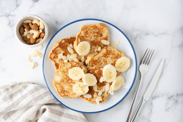 Banana protein pancakes Banana protein pancakes with almond flakes on plate, white marble background, top view pancake stock pictures, royalty-free photos & images