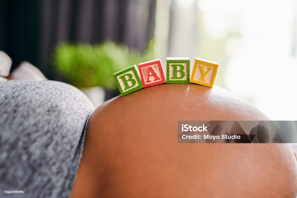 Shot of a unrecognizable pregnant woman laying down with wooden baby blocks on her belly at home A baby is God’s opinion that life should go on Abdomen Stock Photo