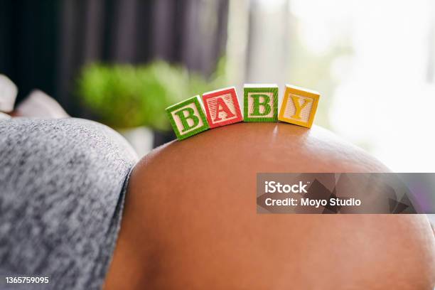 Shot Of A Unrecognizable Pregnant Woman Laying Down With Wooden Baby Blocks On Her Belly At Home Stock Photo - Download Image Now