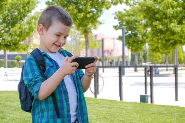 istock Happy schoolboy looking at smartphone screen and smiling 1365759980