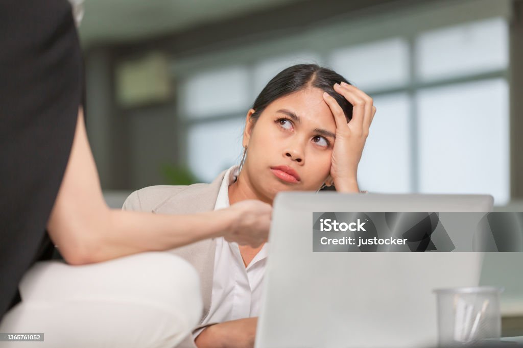 Woman looking at her coworker with a displeased expression, woman working in her office Irritation Stock Photo