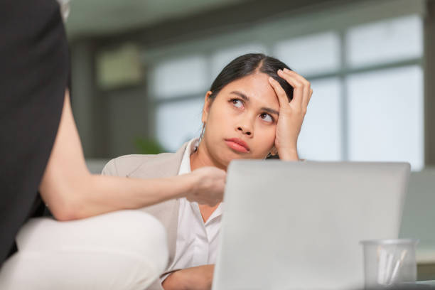 woman looking at her coworker with a displeased expression, woman working in her office - behavior women anger pointing imagens e fotografias de stock