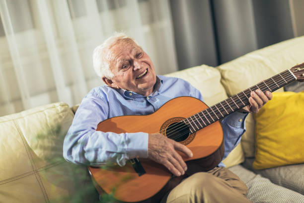 istock Senior man playing guitar at home 1365763480