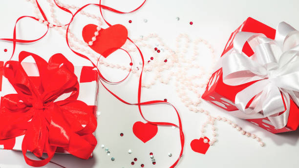 istock Valentine gift boxes with red ribbon bow,red paper hearts on white background. Banner design for St Valentines Day. Love and romance concept. 1365765530