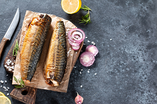 Smoked Fish Mackerel. On a black stone background. Top view. Free copy space.