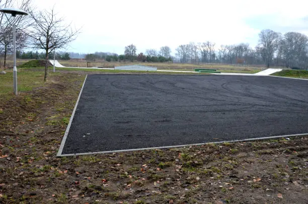 recycled asphalt crumb is used on the edge of the new cycle path and in the subsoil of the asphalt road. between the field and the path behind the curb a parking lot.