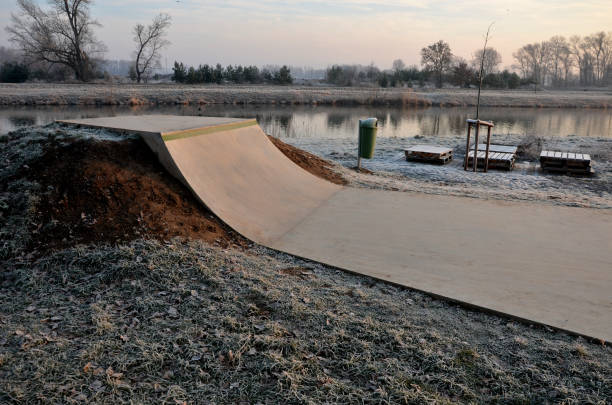 Skateboard park with concrete cement surface with concrete skateboard obstacles is designed for roller sports. Cycling is not allowed except for freestyle bikes. Protective clothing, head, elbow knee, skateboarder, children, teenager, cycling, jump el parque de monopatines con superficie de cemento de hormigón con obstáculos de hormigón está diseñado para deportes de rodillos. el ciclismo no está permitido, excepto para las bicicletas de estilo libre. glaseado amanecer de la mañana de invierno