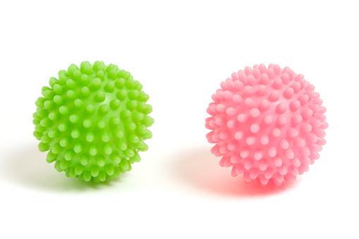 Two prickly plastic balls green and pink on white background