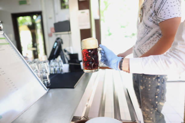 istock Waiter give glass with beer to client in protective glove, prevent covid spread 1365781459