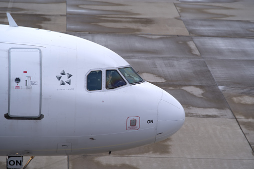 Close-up of cockpit of Swiss airplane Airbus A321-212 register HB-ION taxiing to runway with pilot waving at Zürich Airport on a cloudy winter day. Photo taken January 8th, 2022, Zurich, Switzerland.