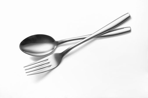 The metal shiny spoon and fork on white background