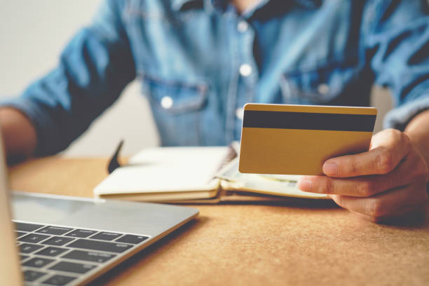 istock Hands holding credit card with using laptop. 1365783950