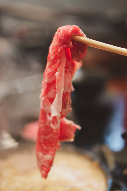 istock Hand holding premium rare slices beef with high-marbled texture with chopsticks. 1365784689