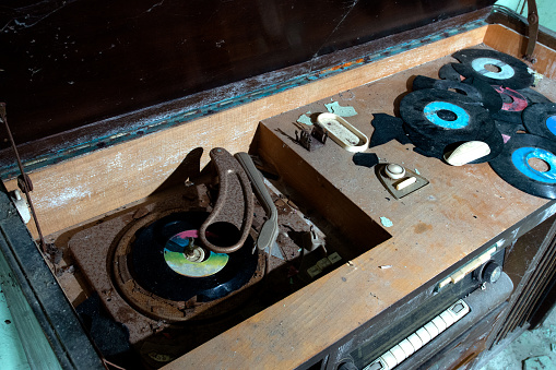Old radio, gramophone and vinyl records in abandoned house.