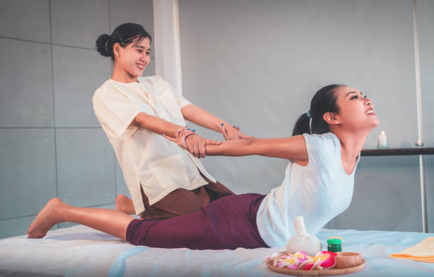 Woman is receiving Back Massage Stretching in Thai Therapy Spa treament. stock photo