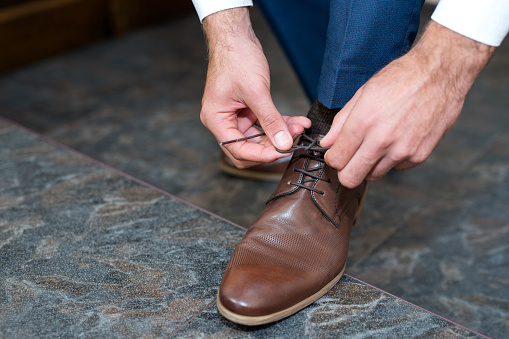 A young man ties the laces of his shoes - detail, selective fokus