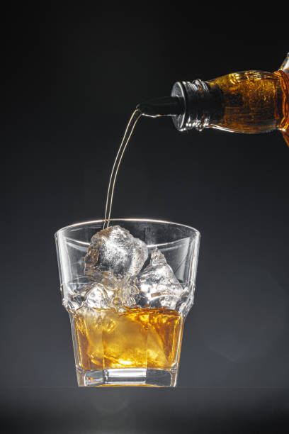 istock Whisky pouring into a glass on black background 1365790170