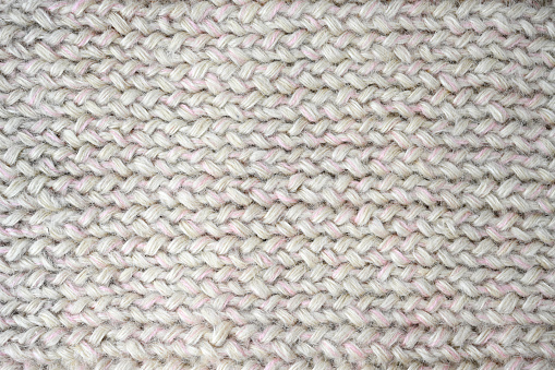 Knitwear gray-white large knitting lies on the table. View from above. Flat lay, top view, close-up, macro, can be used for background.