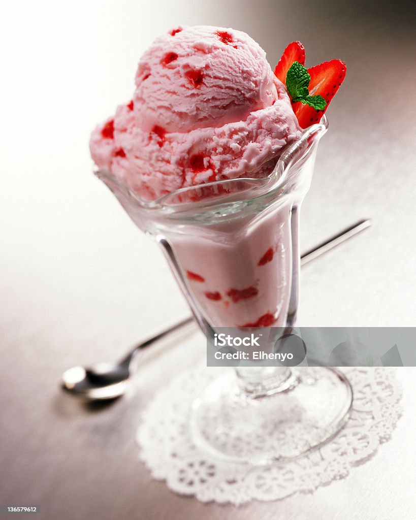 Strawberry ice cream Selective focus image of strawberry ice cream in a fountain parfait glass with a long handled spoon and a doily. Candy Stock Photo