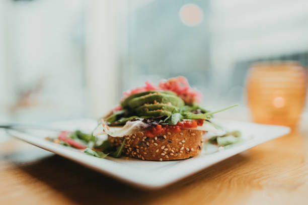 Plate with avocado toast with vegan cheese and vegetables for breakfast on a table in a restaurant