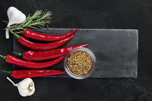 Red hot chili peppers and other spices on dark background, top view