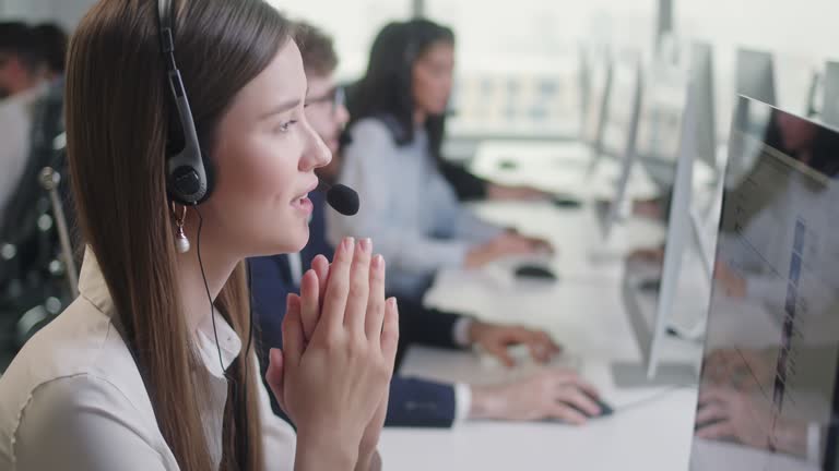 Portrait of a Technical Customer Support Specialist Talking on a Headset while Working on a Computer in Call center and helpful customer service 24-7. Use desktop pc at computer table and phone line at modern co-working