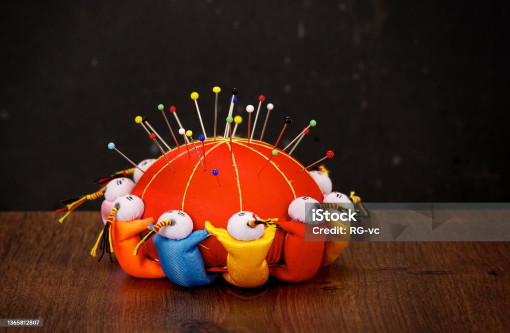 Red pincushion with colorful pins on wooden table and dark background Circle Stock Photo