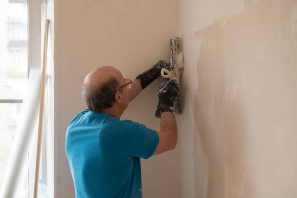 istock Senior man with putty knife plastering repairing wall 1365821062