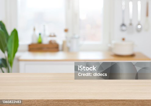 istock Empty wooden desk on blurred kitchen window for product presentation 1365822483
