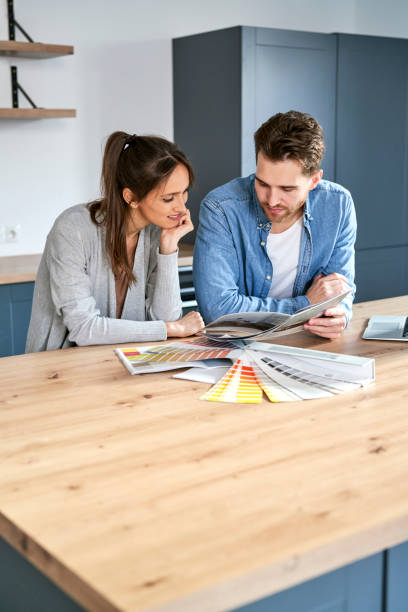 Vertical image of caucasian couple choosing colors for new flat stock photo