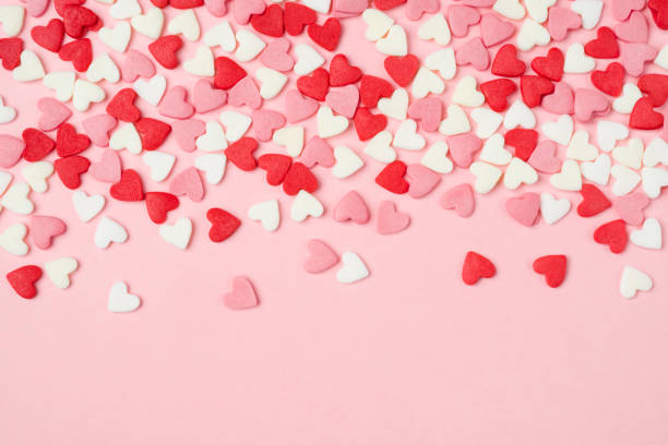 Many colorful sugar hearts on pink background with copy space stock photo