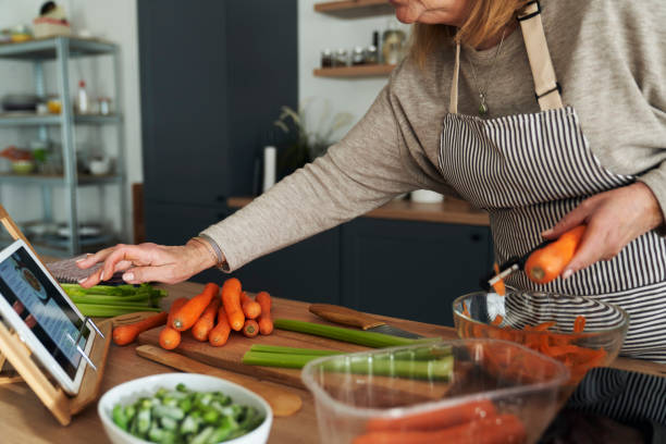 istock Unrecognizable caucasian senior woman using digital tablet while cooking in the domestic kitchen 1365826358