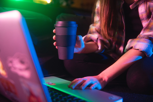 Young woman using computer and holding a mug of coffee