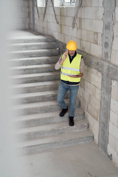 istock Caucasian engineer walking on stairs and browsing digital tablet on construction site 1365831652