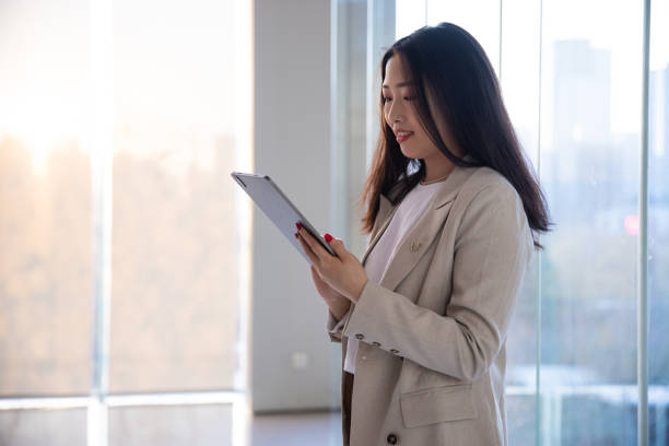 istock Businesswoman using a digital tablet while standing in front of windows 1365831869
