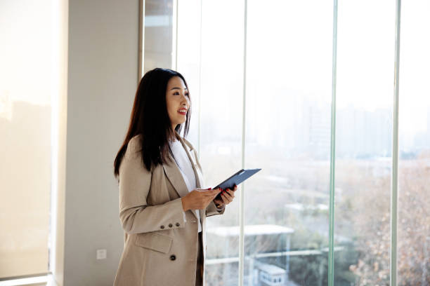 istock Businesswoman using a digital tablet while looking out of windows 1365831924