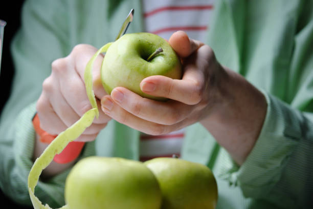 Peeling an apple Human hands are peeling a green apple peeling food stock pictures, royalty-free photos & images