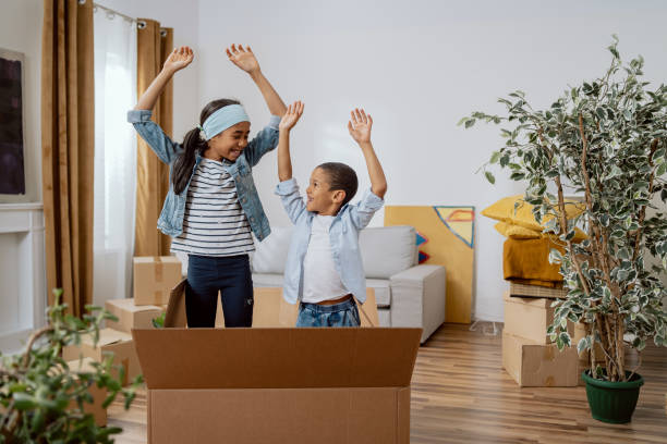 istock Siblings play while moving in empty cardboard boxes, new apartment, renovation, renting a house, hide between packed things, jump up, joy, childhood, girl takes care of younger boy 1365835933