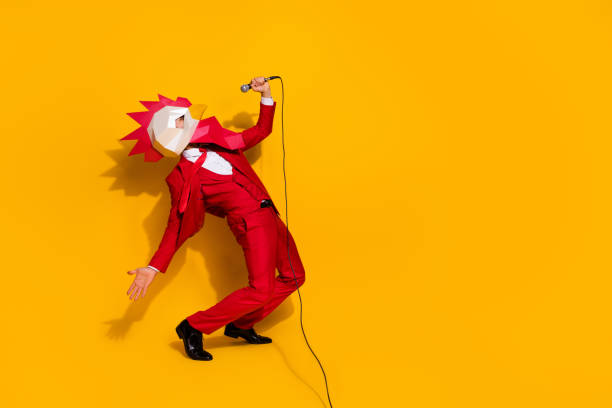 photo of funky carefree incognito guy hold mic sing song wear rooster mask red tux isolated yellow color background - tavuk kostümü stok fotoğraflar ve resimler