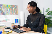 Attractive, experienced, company secretary sits in office in front of a computer tapping fingers on keyboard writing e-mails, filling out documents, reports, preparing minutes for manager