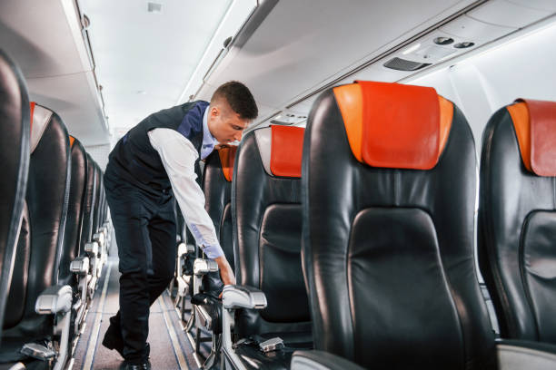 istock Young steward in uniform on the work in the passanger airplane 1365846648