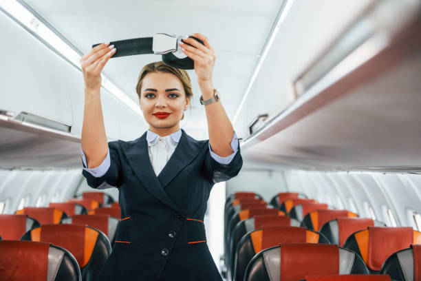 instrucciones de seguridad. joven azafata en el trabajo en el avión del pasajero - aeromoza fotografías e imágenes de stock