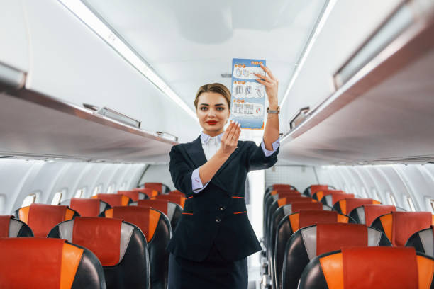 istock Holds paper with instrucitons. Young stewardess on the work in the passanger airplane 1365846748