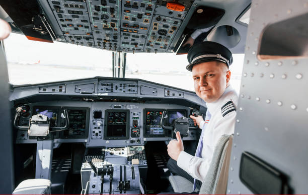 istock Looks behind. Pilot on the work in the passenger airplane. Preparing for takeoff 1365847024