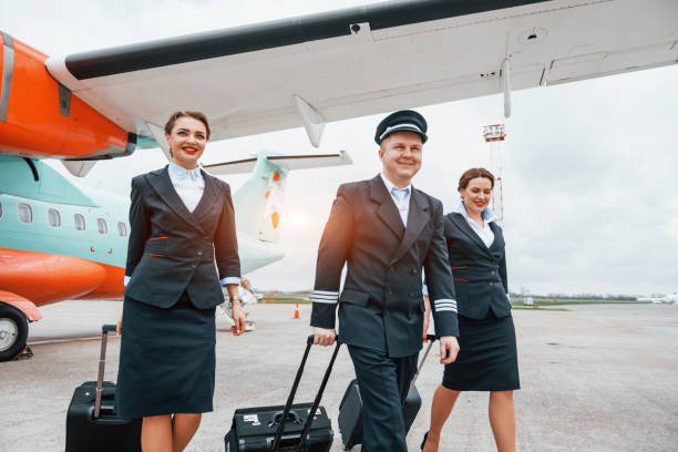 istock With luggage. Aircraft crew in work uniform is together outdoors near plane 1365848355