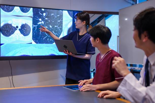 Medical professionals discussing in a conference room Health care and science professionals looking at medical x-rays of patients to find the latest treatment methods. x ray image medical occupation technician nurse stock pictures, royalty-free photos & images