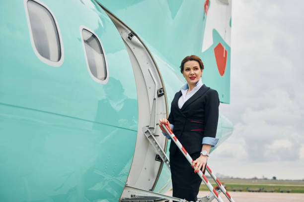 istock Young stewardess posing for the camera outdoors near airplane 1365848436