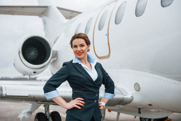 istock Young stewardess posing for the camera outdoors near airplane 1365848519